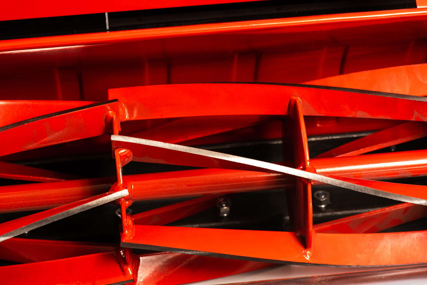 Close-up of the red blades on a professional petrol cylinder mower showing the sharp cutting edges