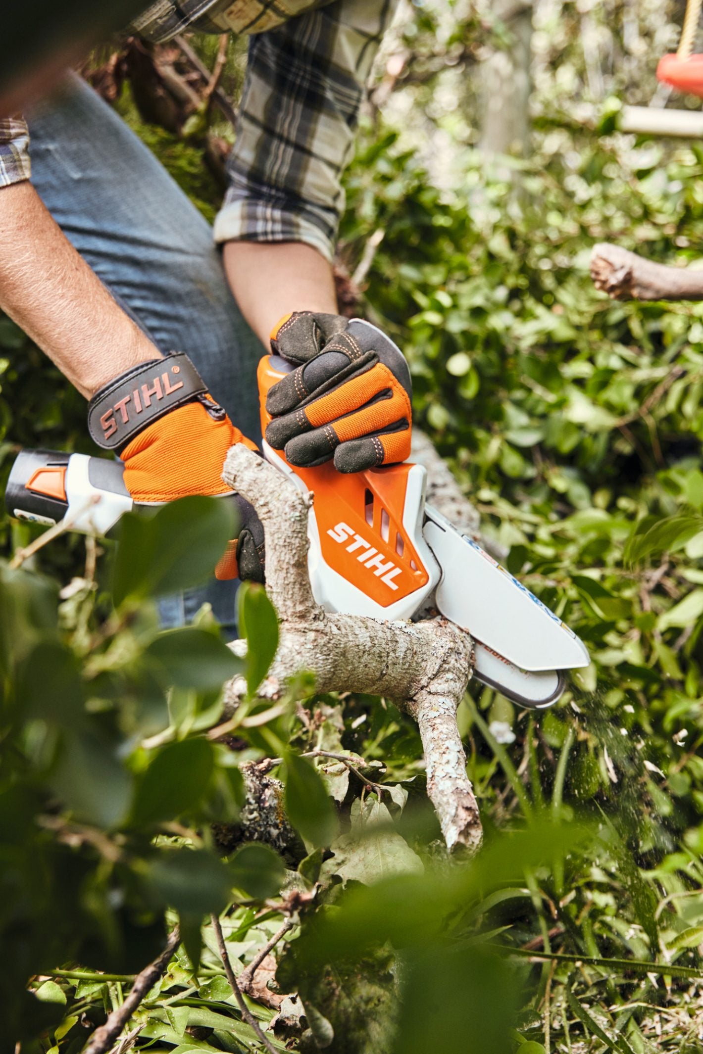 Stihl GTA26 AS2 battery powered chainsaw cutting branch with user wearing protective gloves