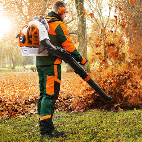 Person using STIHL BR700 blower for sale to clear autumn leaves in a park setting