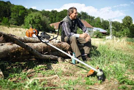 STIHL FS230 brushcutter for sale with man resting on log in rural outdoor setting