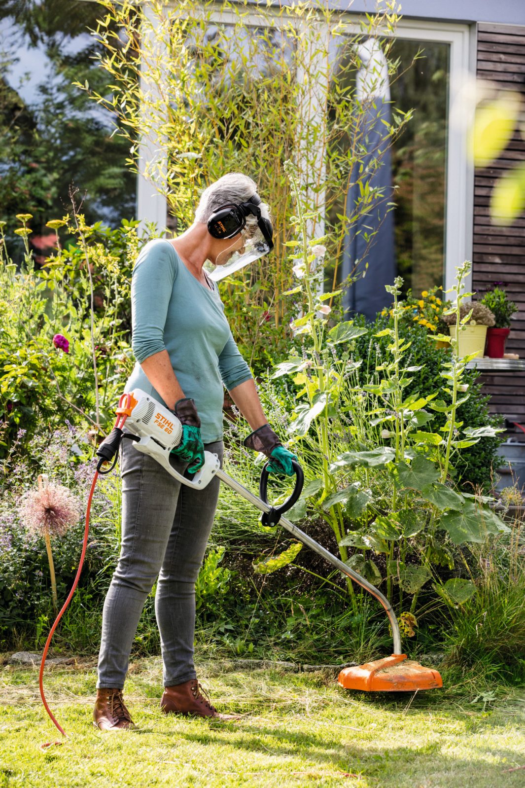 Woman using STIHL FSE60 electric trimmer outdoors for garden and lawn maintenance