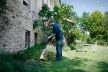 STIHL FSE31 electric trimmer used by man trimming grass near stone house in garden