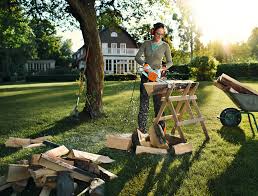 Person using STIHL MSE170 electric chainsaw to cut wood outdoors on a sunny day